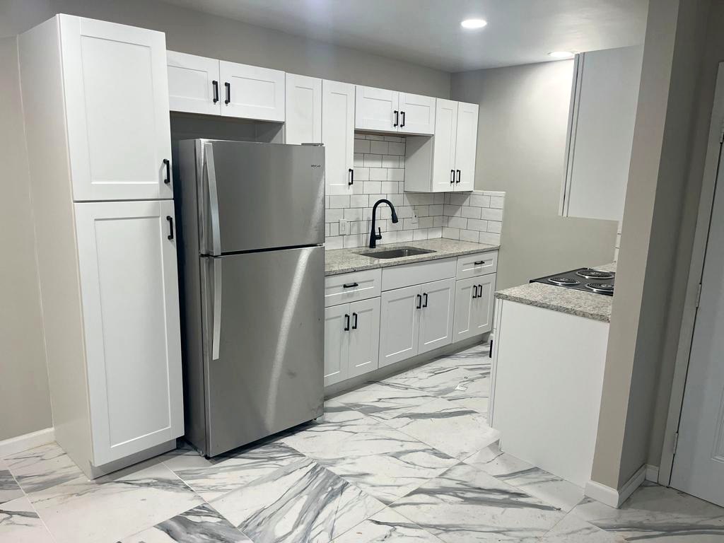 Kitchen with white cabinets, black hardware and stainless refrigerator