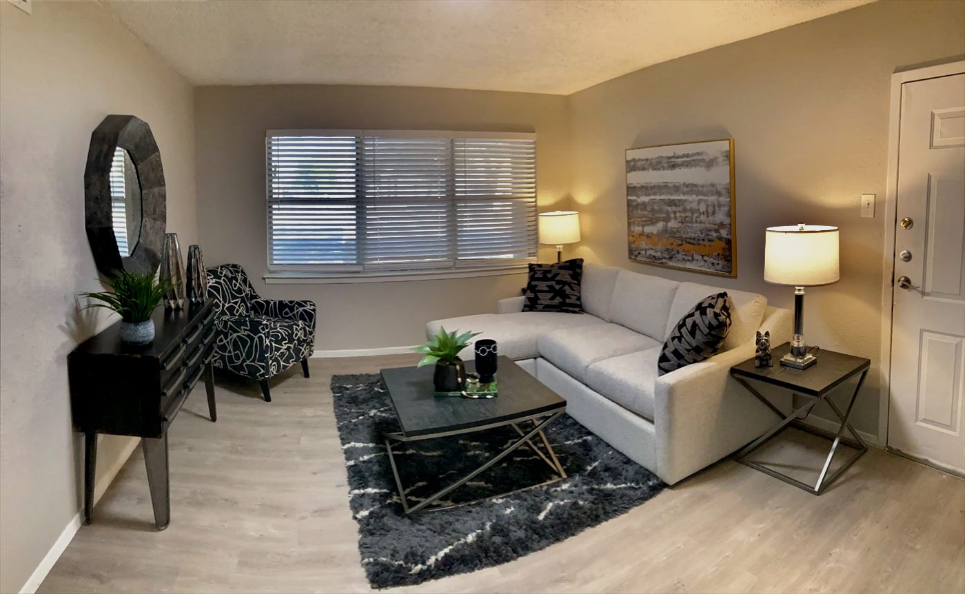 Furnished living room with white sectional sofa, lamps and large window
